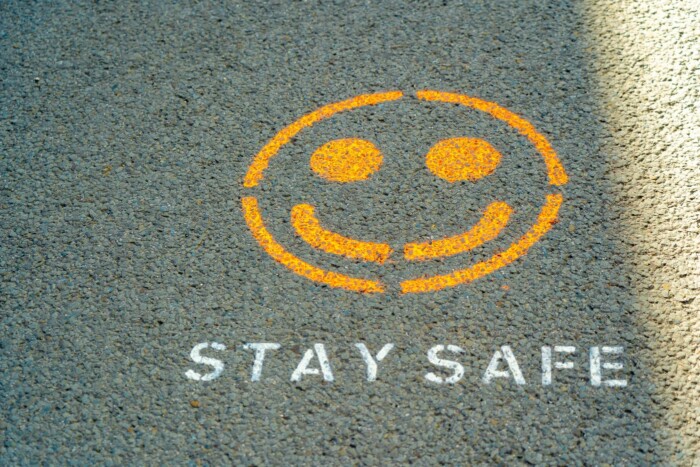 A smiley face painted on the ground with " stay safe " written underneath.